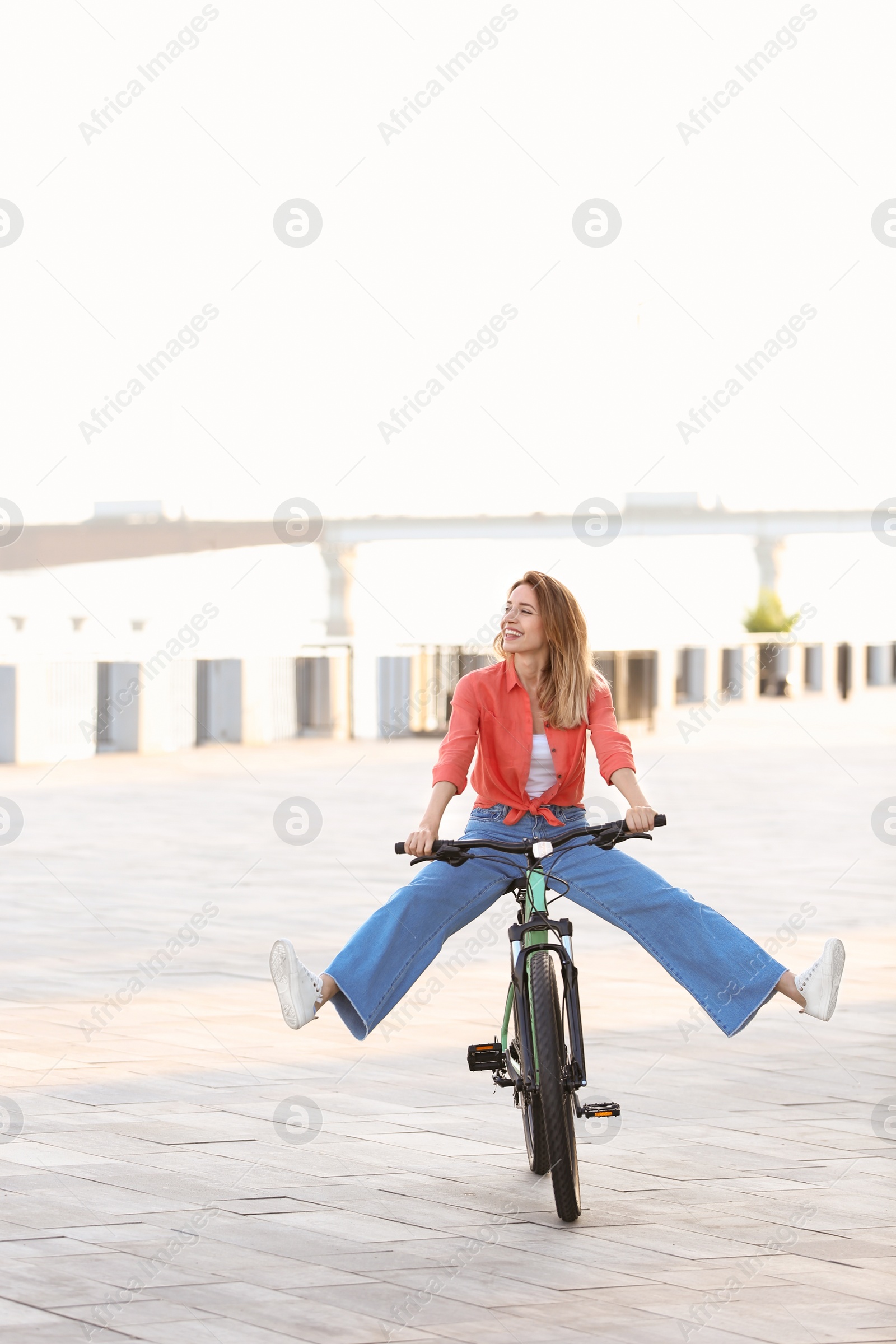 Photo of Happy young woman riding bicycle in city