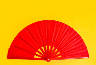 Photo of Red hand fan on yellow background, top view