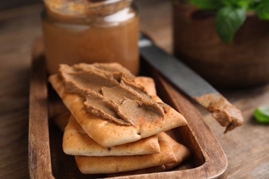 Photo of Crispy crackers with delicious meat pate on wooden table, closeup