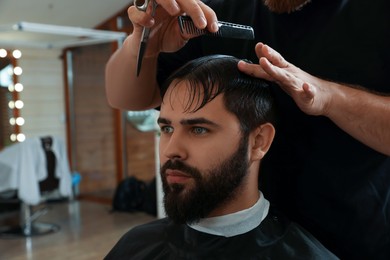 Professional hairdresser working with client in barbershop, closeup