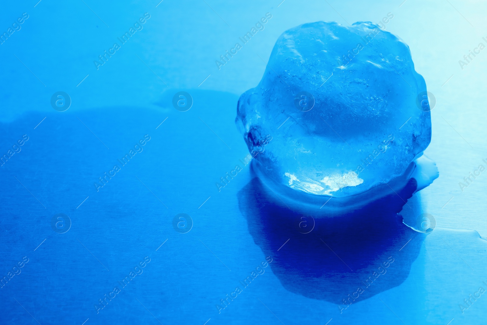 Photo of Crystal clear ice cube on light blue background, space for text. Color tone effect