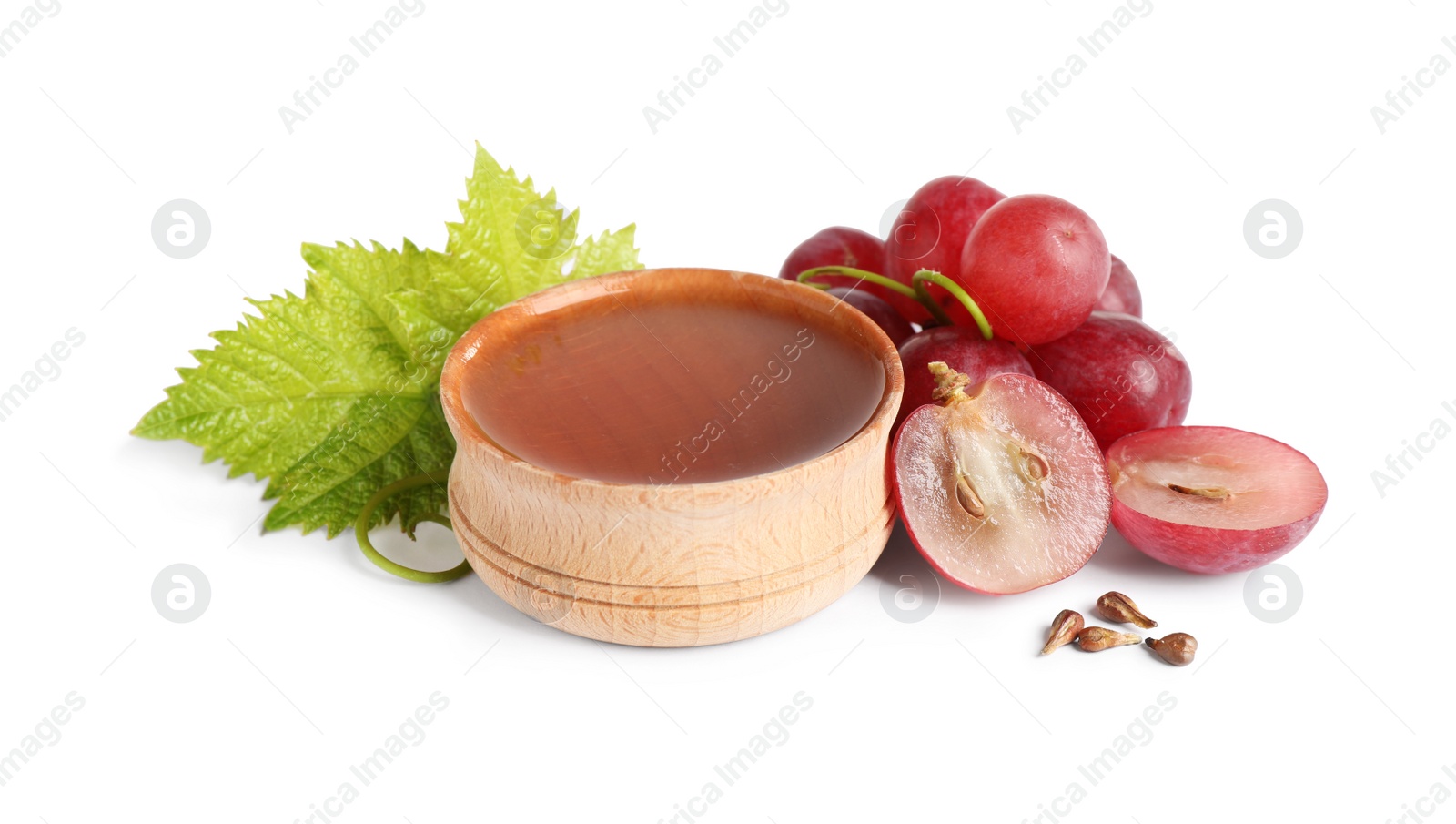 Photo of Organic red grapes, seeds and bowl of natural essential oil on white background