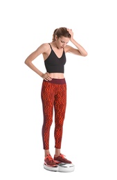 Photo of Sad young woman measuring her weight using scales on white background. Weight loss motivation