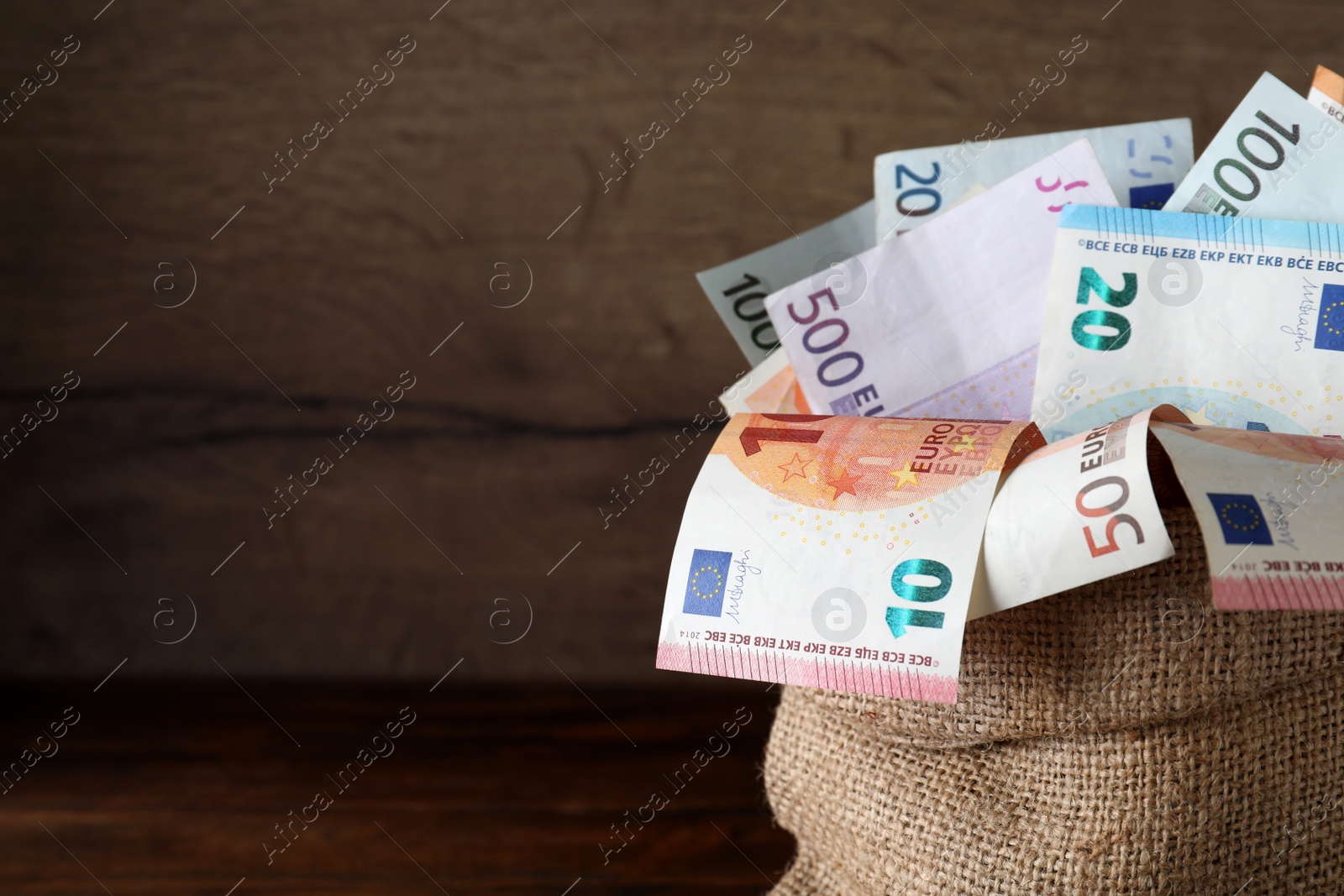 Image of Sack full of money on wooden table, closeup. Space for text 