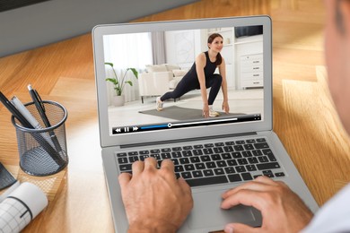 Image of Man watching morning exercise video on laptop at table, closeup
