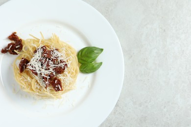 Photo of Tasty spaghetti with sun-dried tomatoes and parmesan cheese on white table, top view and space for text. Exquisite presentation of pasta dish