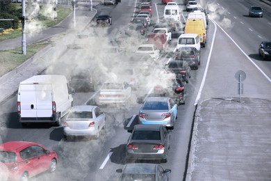Image of Environmental pollution. Air contaminated with fumes in city. Cars surrounded by exhaust on road