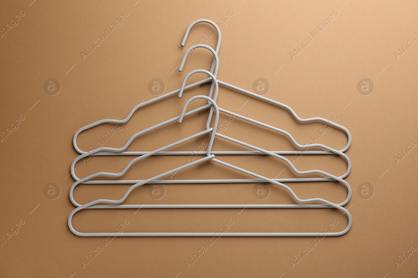 Photo of Empty hangers on brown background, top view