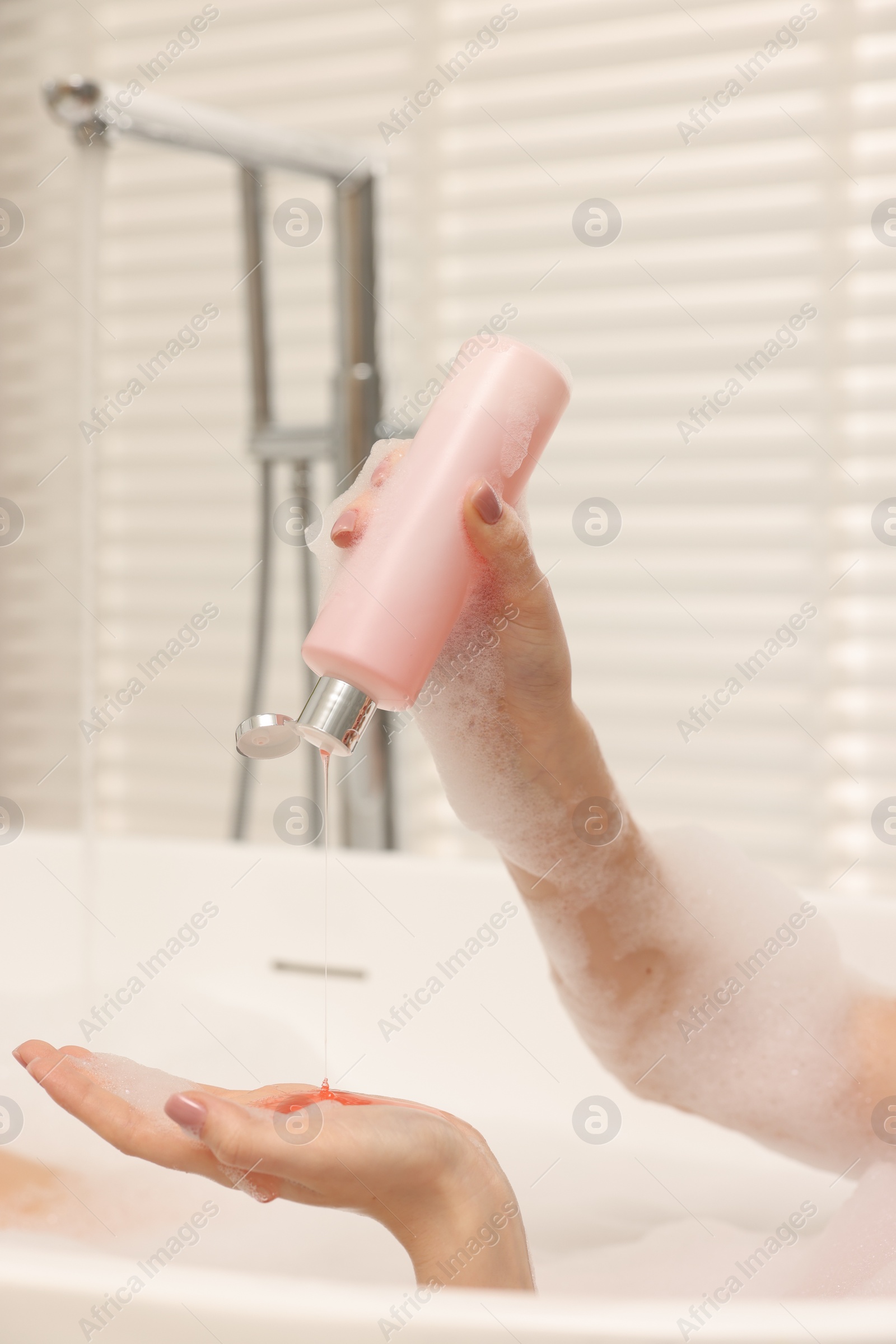 Photo of Woman pouring shower gel onto hand in bath indoors, closeup