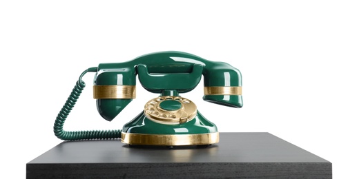 Photo of Green vintage corded phone on small black table against white background