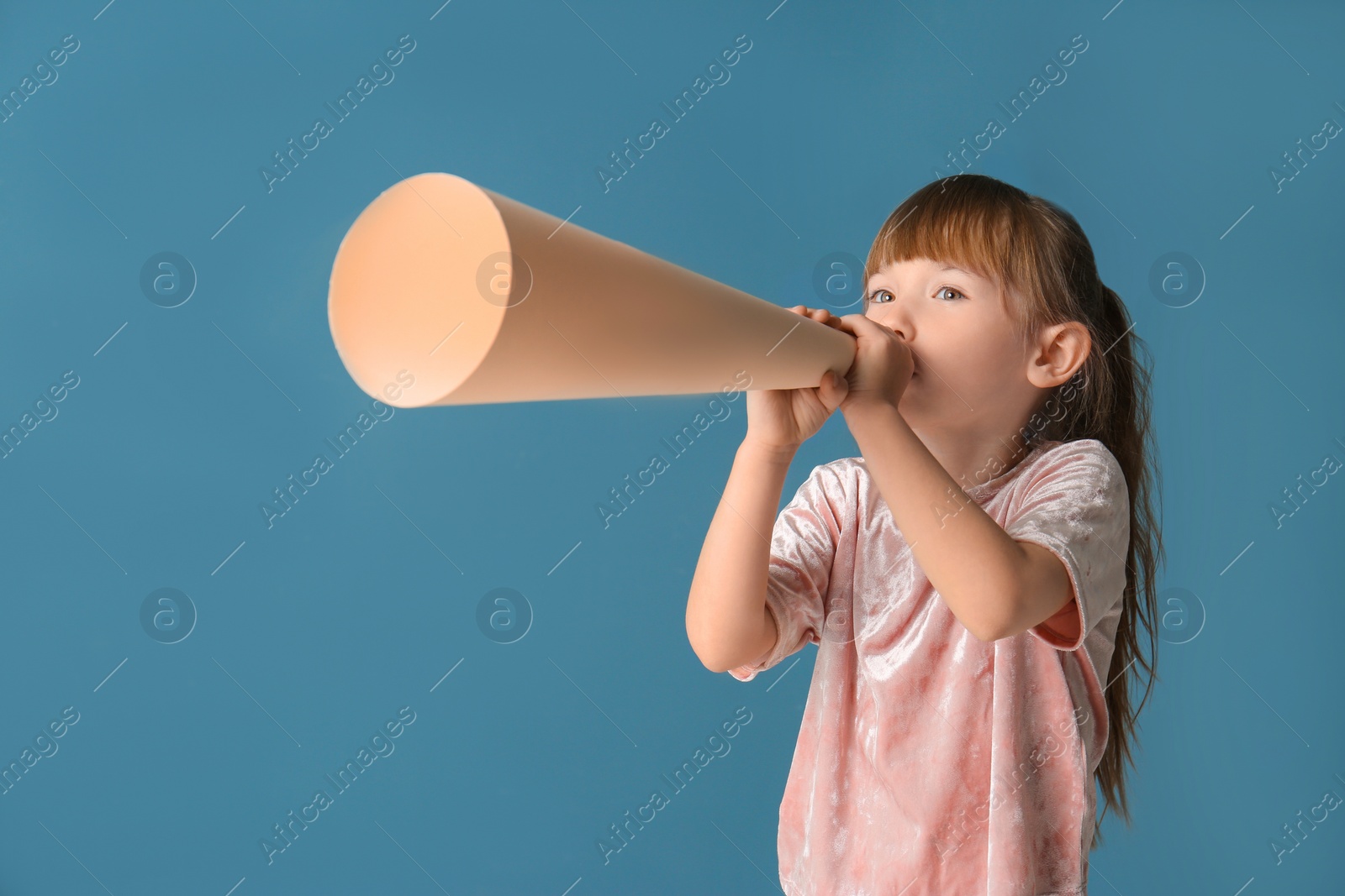 Photo of Cute little girl with paper megaphone on color background