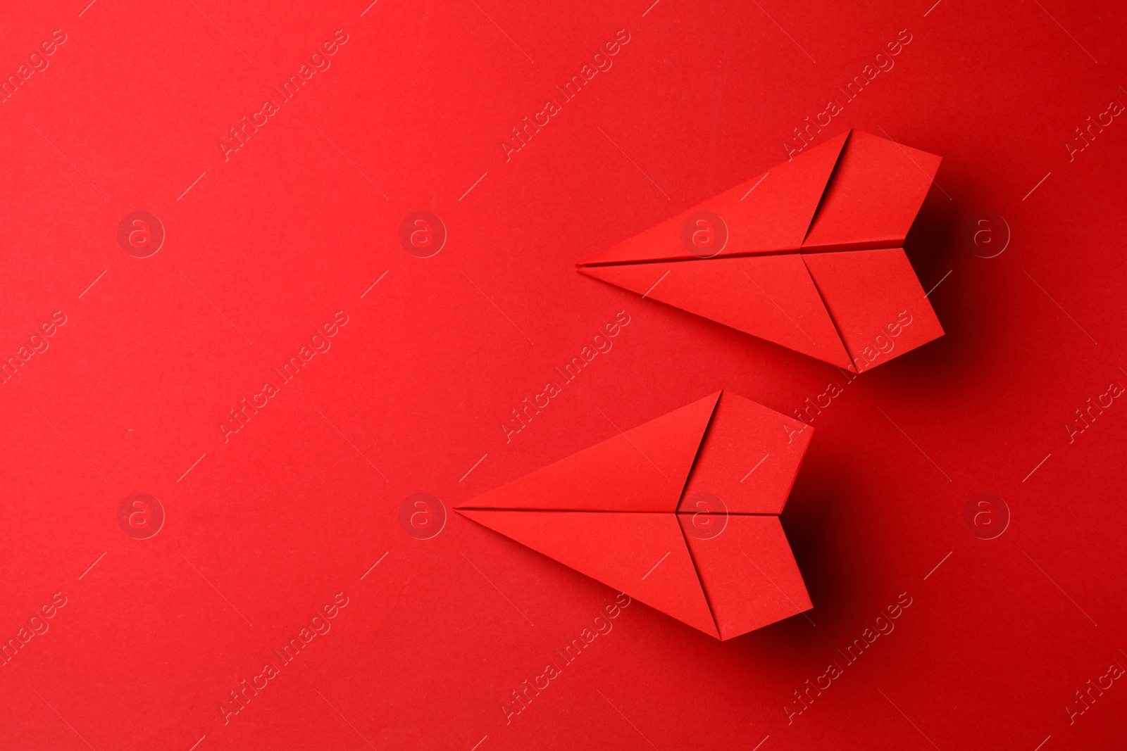 Photo of Handmade paper planes on red background, flat lay. Space for text