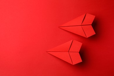 Photo of Handmade paper planes on red background, flat lay. Space for text