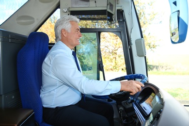 Photo of Professional bus driver at steering wheel. Passenger transportation