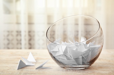 Paper pieces for lottery in glass vase on wooden table. Space for text