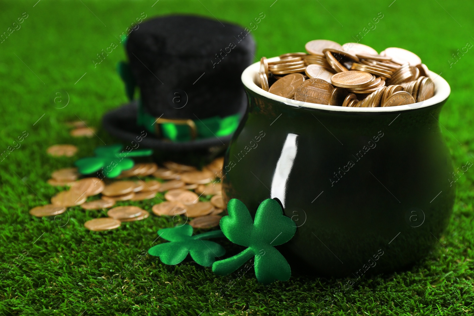 Photo of Pot of gold coins, hat and clover leaves on green grass, space for text. St. Patrick's Day celebration