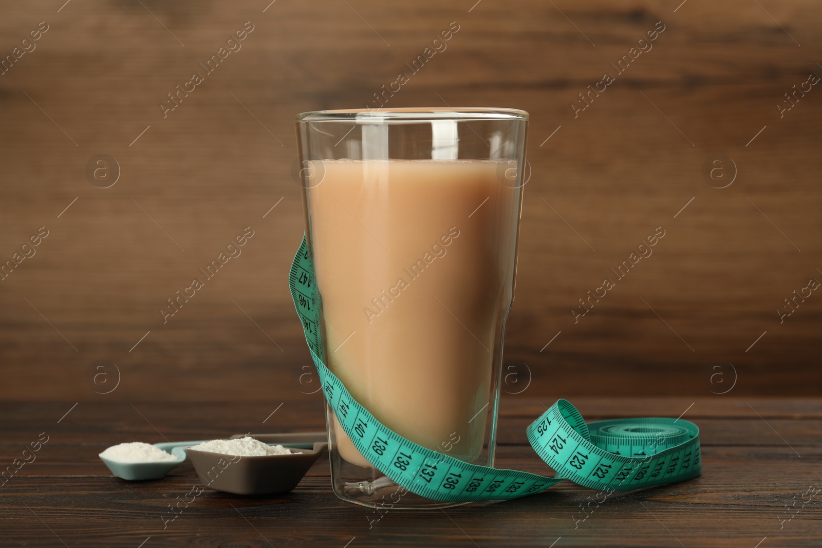 Photo of Tasty shake, measuring tape and powder on wooden table. Weight loss