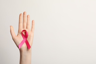 Photo of Woman holding pink ribbon on white background, top view. Cancer awareness