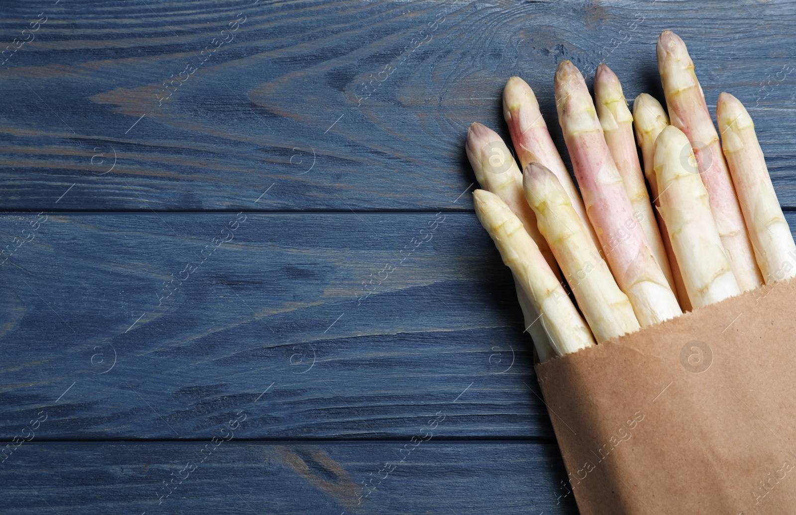 Photo of Fresh white asparagus on blue wooden table, top view. Space for text