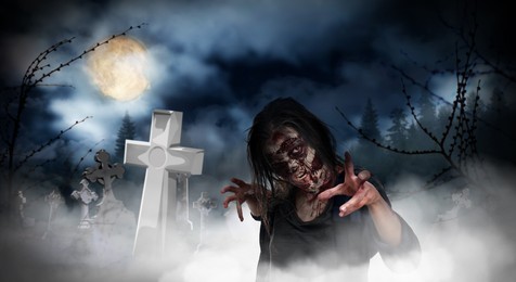 Scary zombie at misty cemetery with old creepy headstones under full moon. Halloween monster