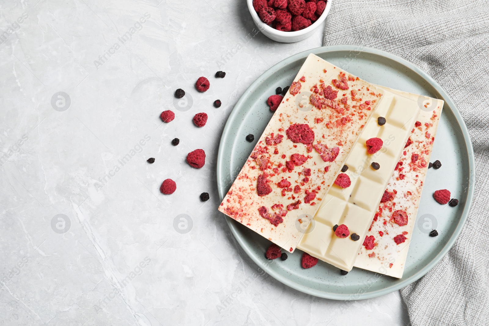 Photo of White chocolate bars with freeze dried fruits on grey marble table, flat lay. Space for text