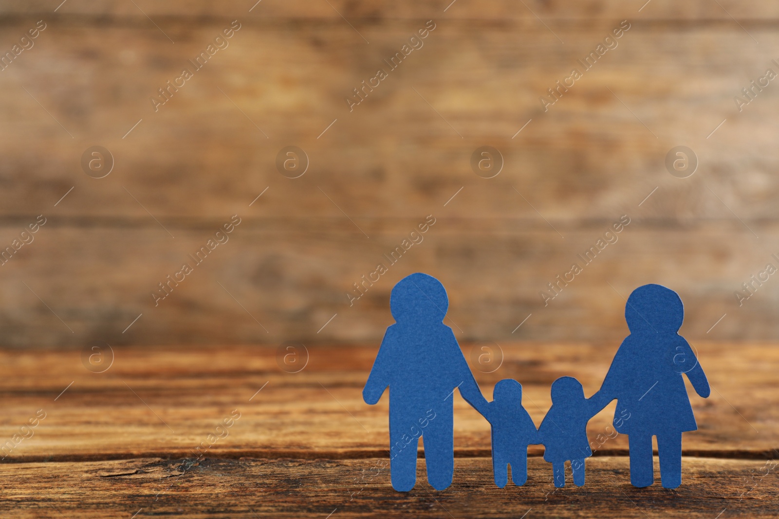 Photo of Paper family figure on wooden table, space for text. Child adoption concept