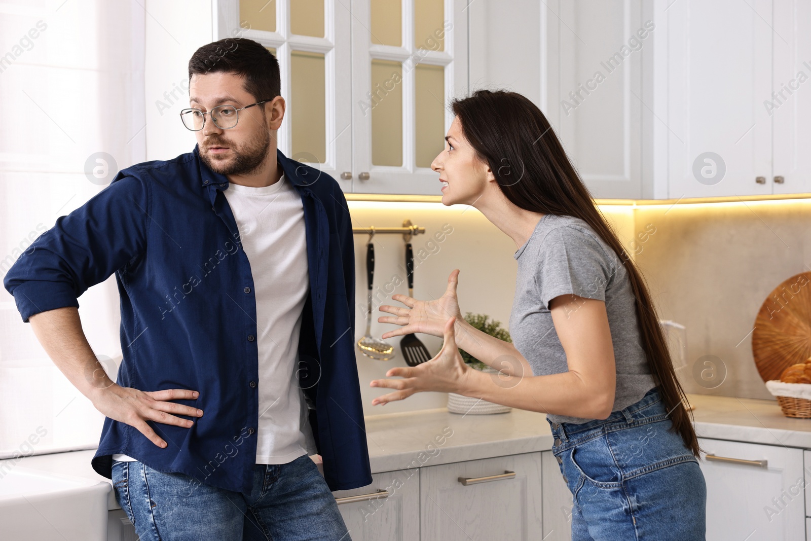 Photo of Annoyed wife screaming at her husband in kitchen. Relationship problems