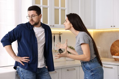 Photo of Annoyed wife screaming at her husband in kitchen. Relationship problems