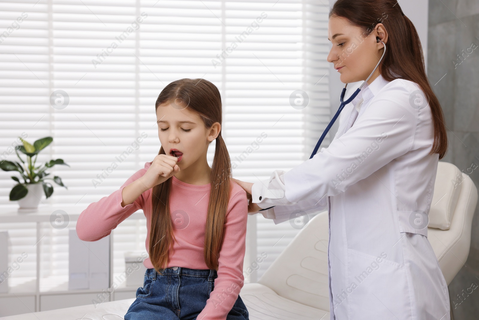 Photo of Doctor examining coughing girl in hospital. Cold symptoms