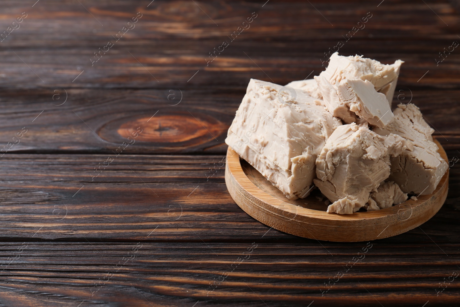 Photo of Compressed yeast on wooden table, space for text