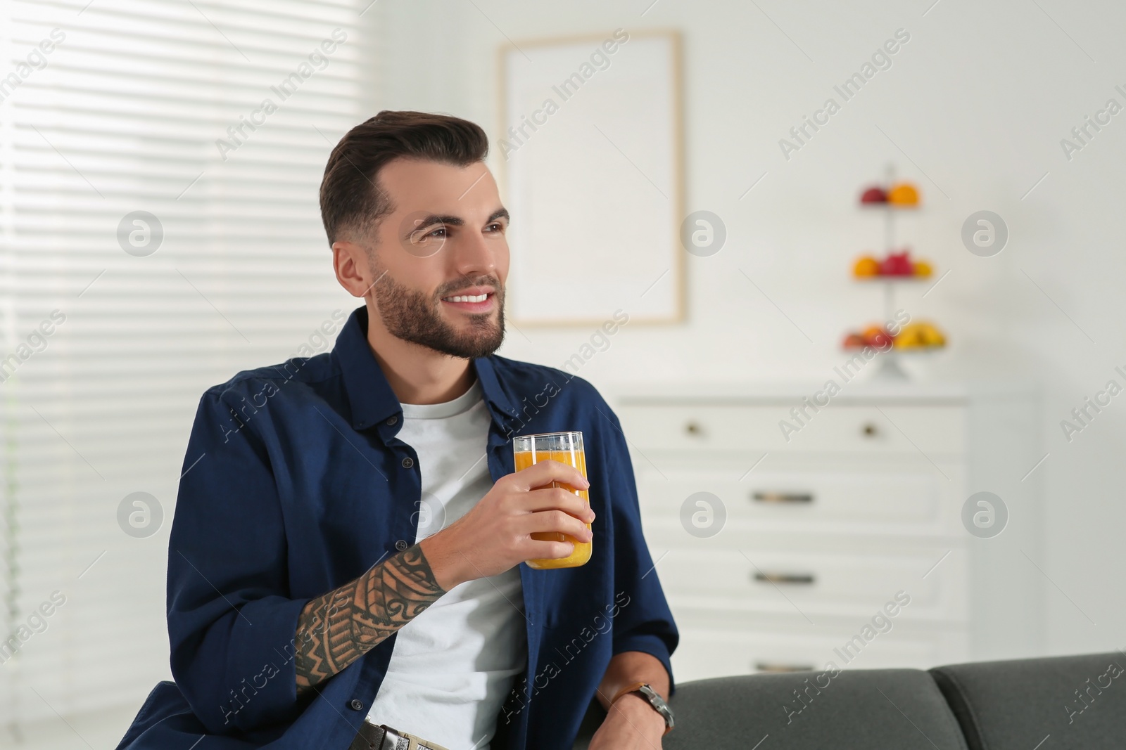 Photo of Handsome man with delicious smoothie at home. Space for text