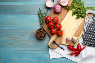 Cutting board and vegetables on blue wooden table, flat lay with space for text. Cooking utensil