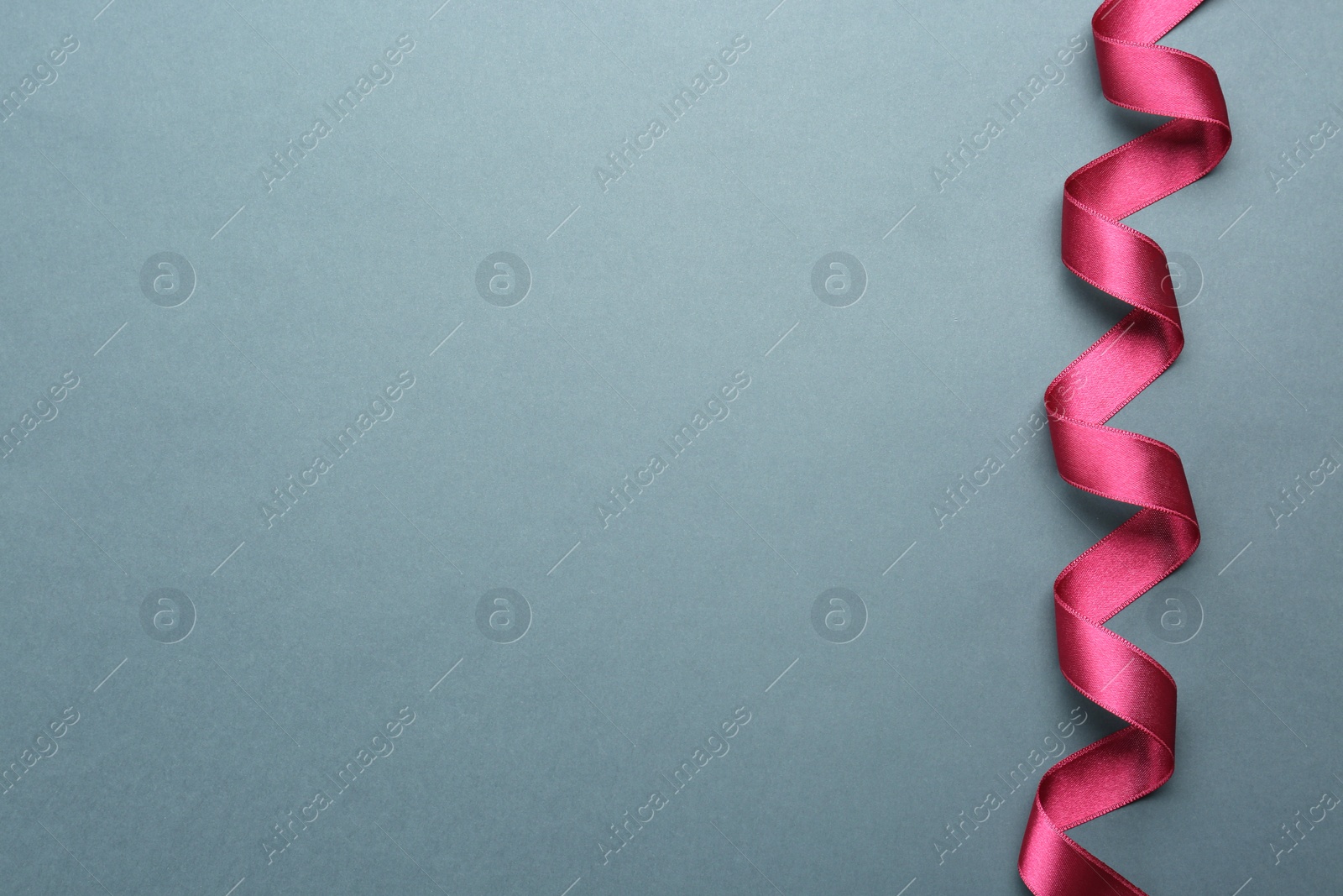 Photo of Beautiful pink ribbon on grey background, top view. Space for text