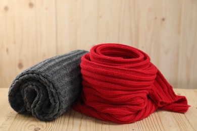Photo of Red and gray knitted scarfs on wooden table