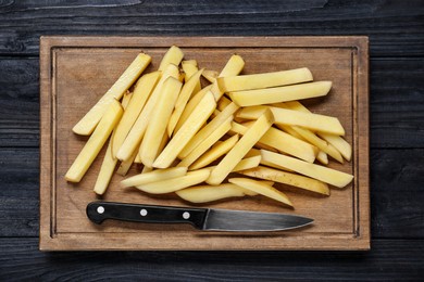 Photo of Cut raw potatoes on black wooden table, top view