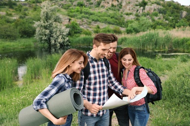 Photo of Group of young people exploring map in wilderness. Camping season