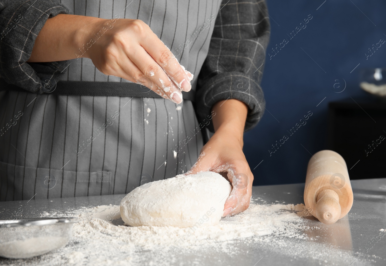 Photo of Woman sprinkling dough for pastry with flour on table