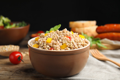 Photo of Tasty buckwheat porridge with vegetables on wooden table