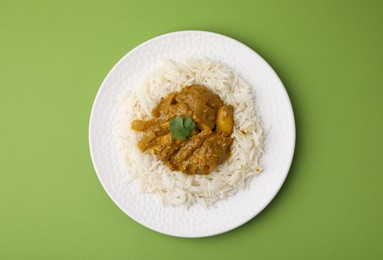 Photo of Delicious chicken curry with rice on green background, top view