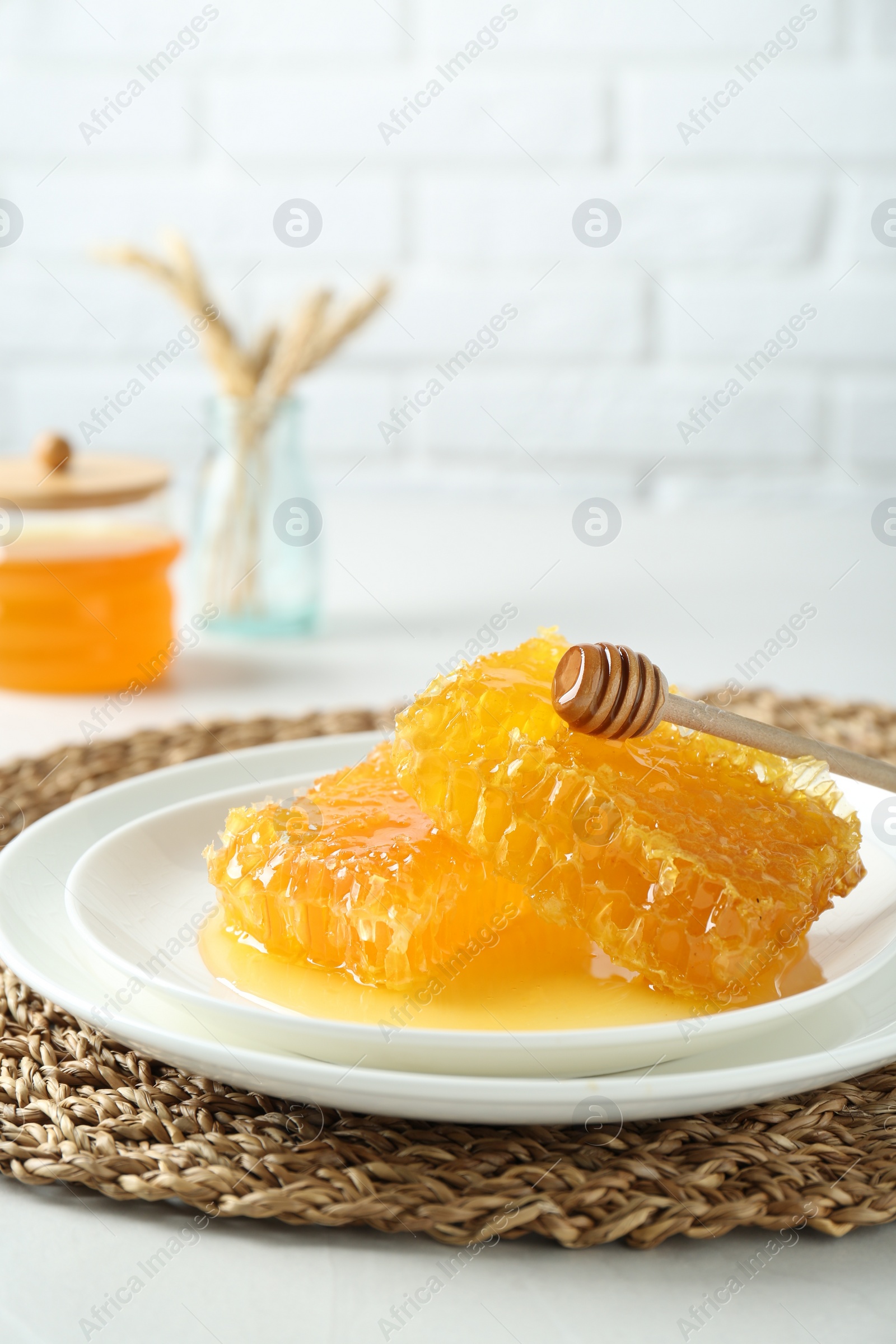 Photo of Natural honeycombs with tasty honey and dipper on white table
