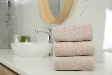 Stack of clean towels on countertop in bathroom. Space for text