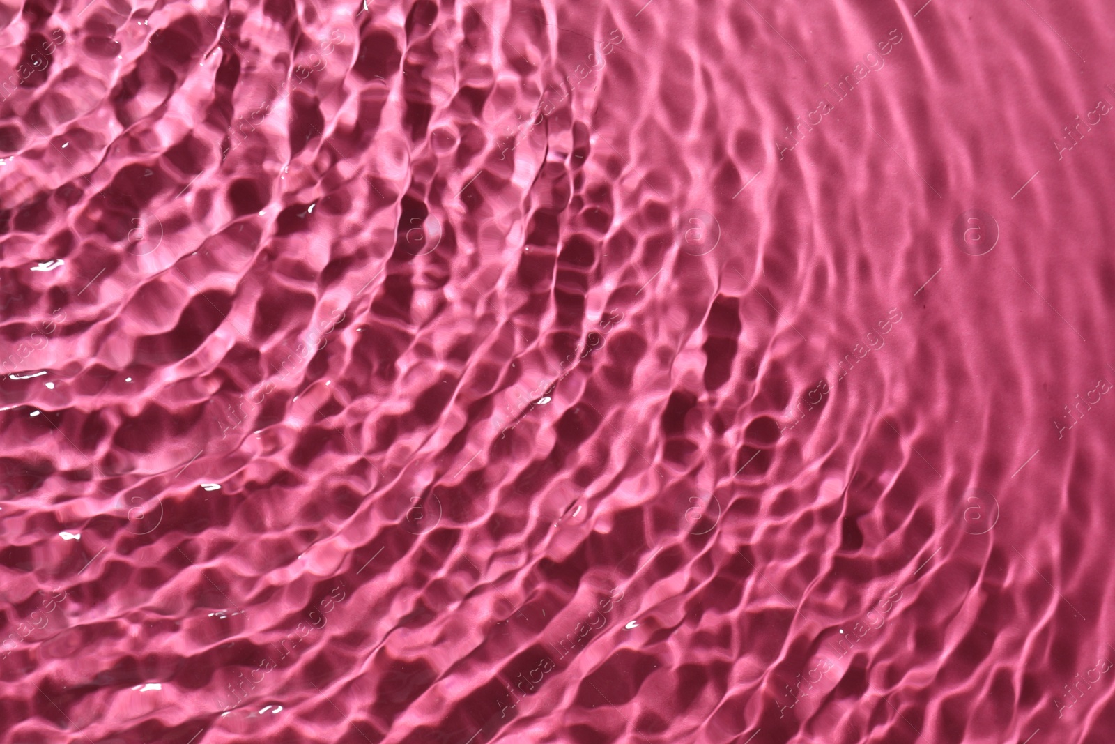 Photo of Rippled surface of clear water on bright pink background, top view