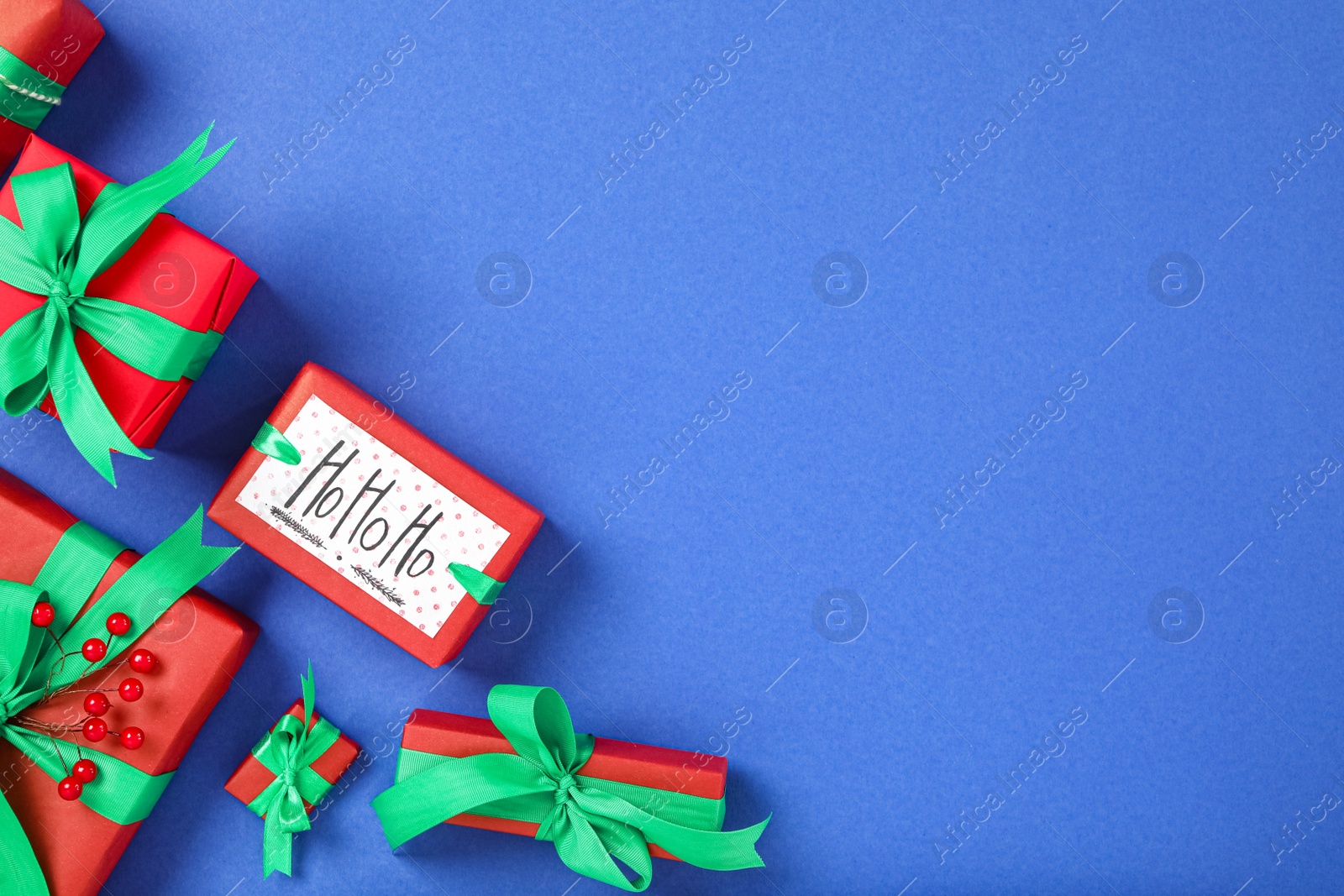 Photo of Different Christmas gift boxes on blue background, flat lay. Space for text