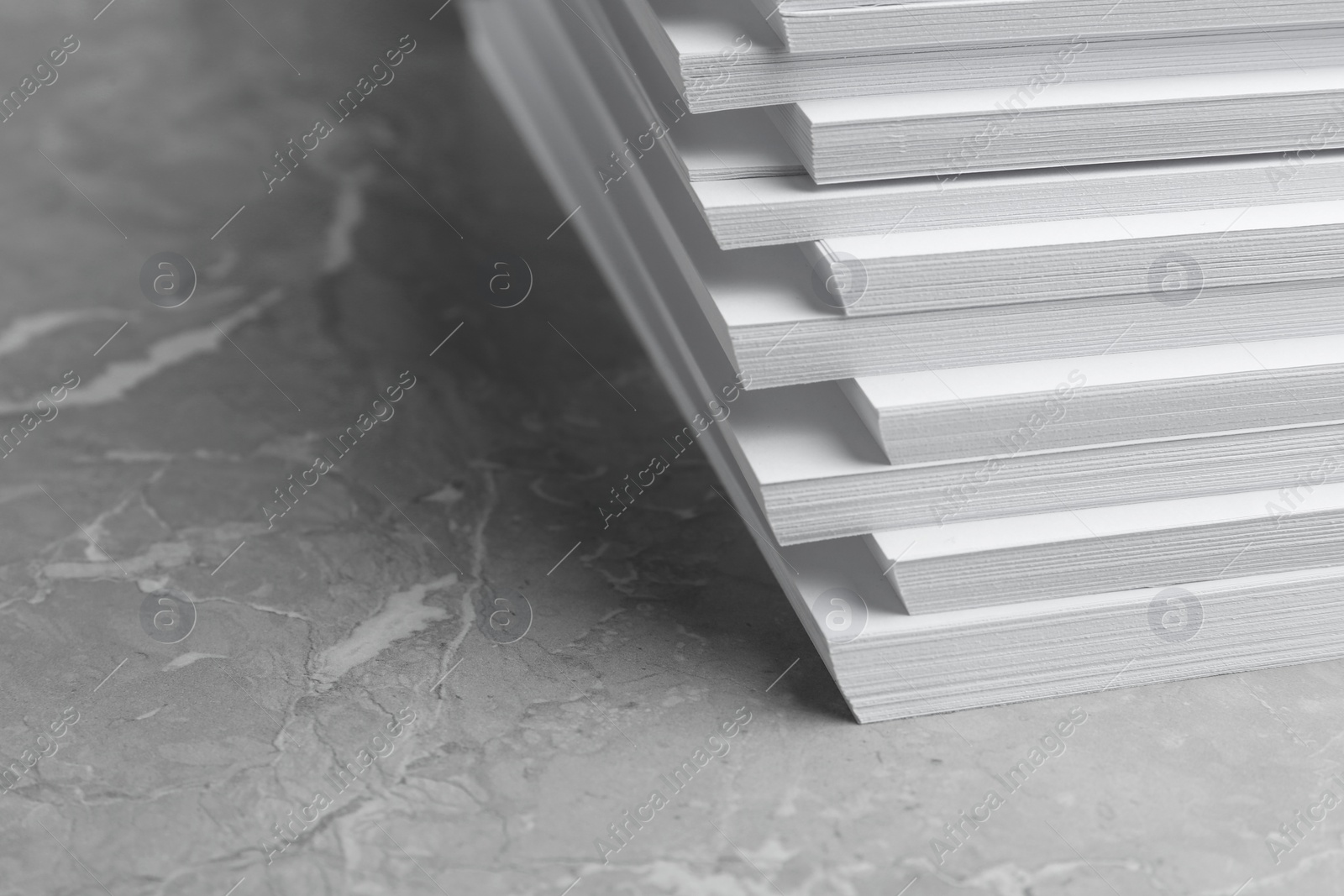 Photo of Stack of blank white paper on marble table, closeup. Space for text