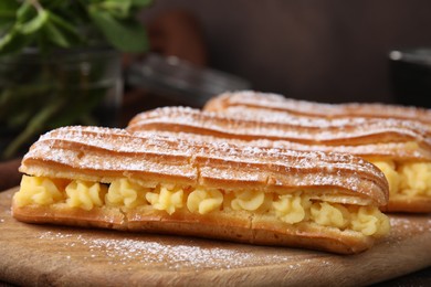 Delicious eclairs filled with cream on table, closeup