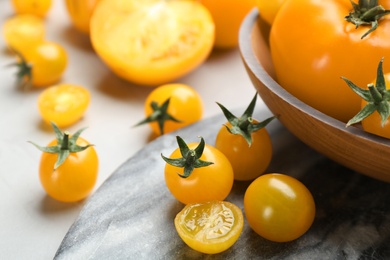 Photo of Ripe yellow tomatoes on marble board, closeup