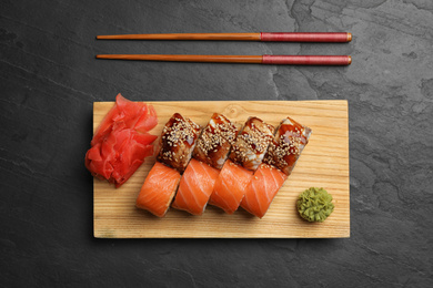 Delicious sushi rolls on dark grey table, flat lay