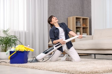 Photo of Happy young housewife having fun while cleaning carpet at home