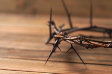 Photo of Crown of thorns on wooden table, closeup with space for text. Easter attribute