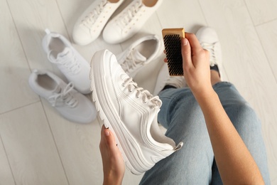 Photo of Woman cleaning stylish footwear indoors, closeup. Shoe care accessory